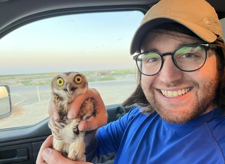 student researcher holding a burrowing owl